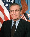 man in business suit, American flag in background