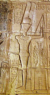 Relief of a man with an erection, wearing a headdress of two feathers and a disk