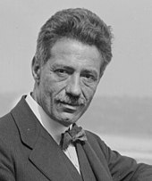 photograph of a middle aged man with a small moustache and bow-tie, looking towards the camera