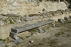 Banc, le long de la paroi arrière de la stoa.