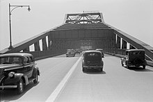 A grayscale photo of a four lane undivided road on a bridge