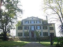 Three-storey mansion surrounded by trees and gardens