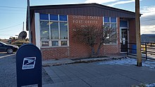 Brick post office building with US flag and blue mail collection box