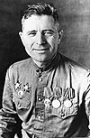 Portait en noir et blanc d'un homme souriant en chemise militaire avec des médailles sur la poitrine