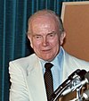 man in business suit, microphones in foreground