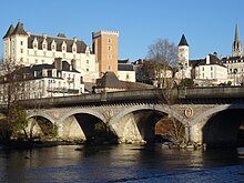 Photographie en couleurs d'un pont enjambant une rivière avec un château en deuxième plan.