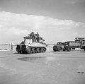 A Sherman BARV tows a disabled Bedford articulated lorry and trailer off the beach, 14 June 1944.