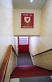 steps leading down to tunnel, above the tunnel is a sign with This Is A Field in white letters on a red background, with a crest on it