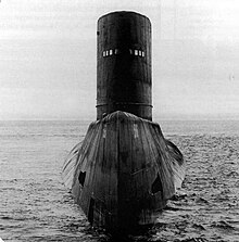 Large submarine surface displaying its bow, upper deck, and large conning tower