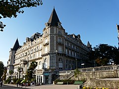 photographie en couleurs d'un grand bâtiment carré à étages, tours dans les angles.