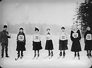 Six femmes portant des skis et un dossard numéroté, se tenant en ligne sur la neige.