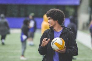 A UW student holds a volleyball while enjoying activities on a field at Dawg Daze
