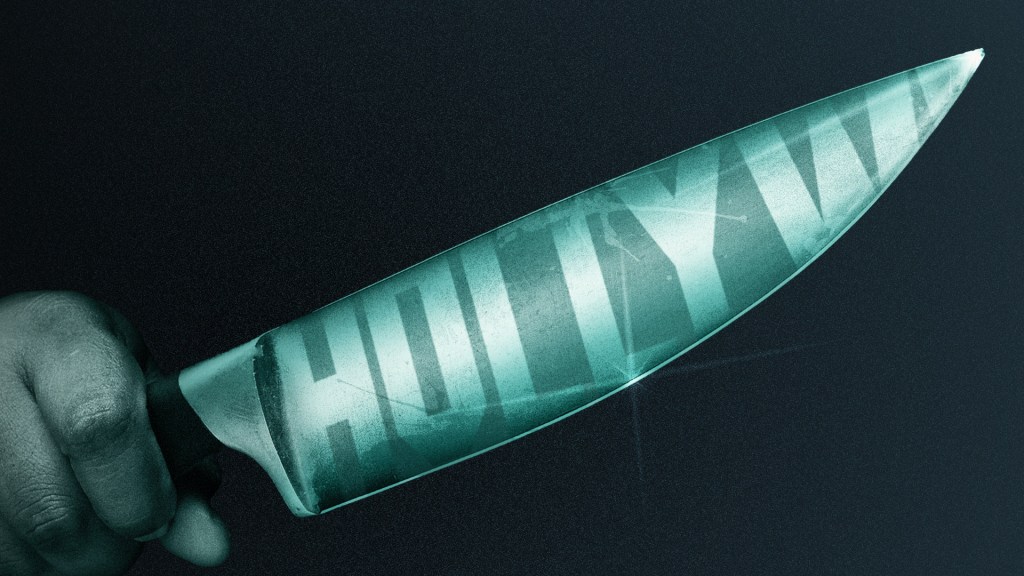 Hand holding a knife with the reflection of the Hollywood sign