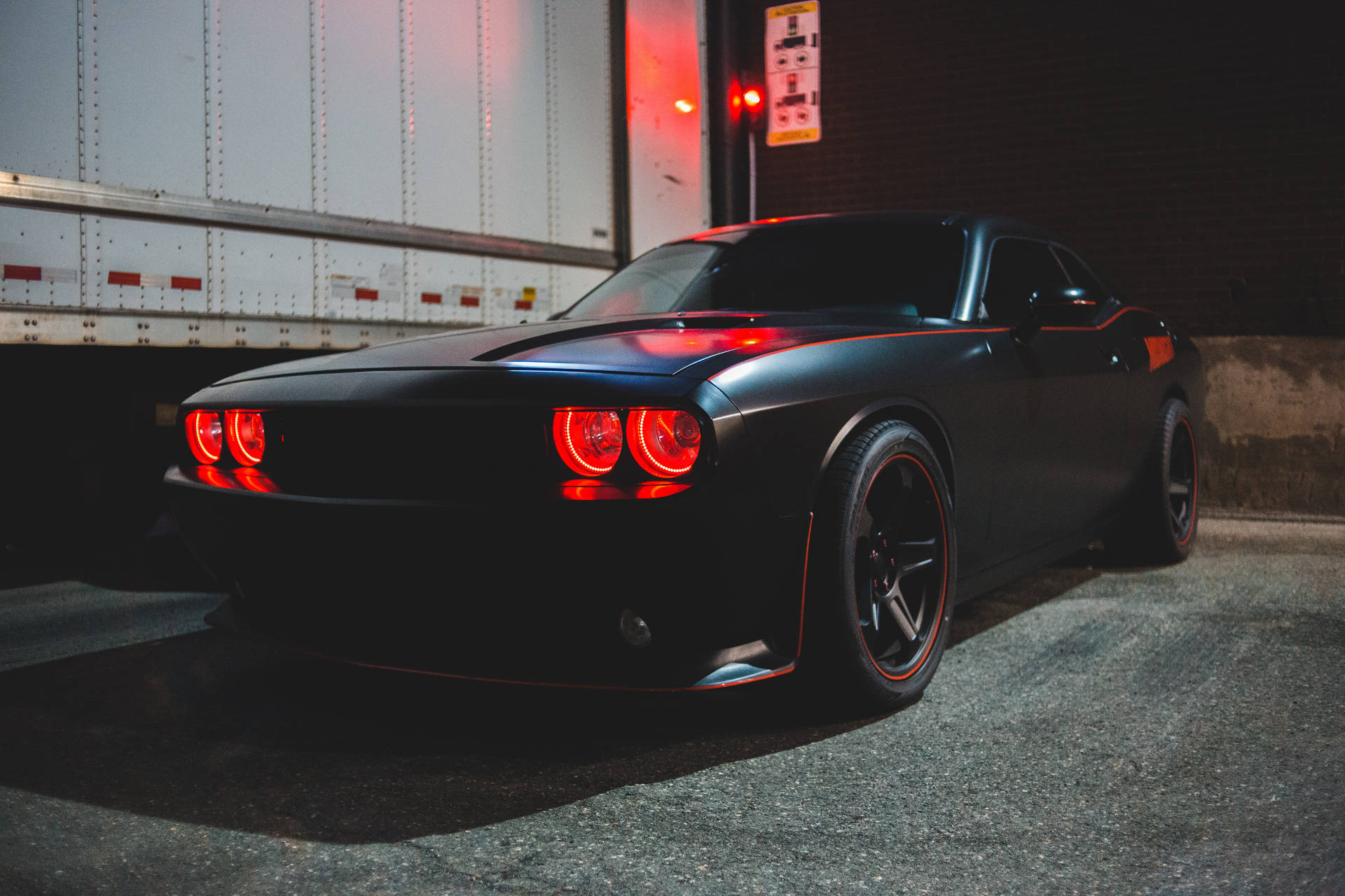 Schwarzer Muscle-Car mit roten Lichtern nachts in der Nähe eines Lastwagens geparkt. — Schwarze Sportwagen Wallpaper