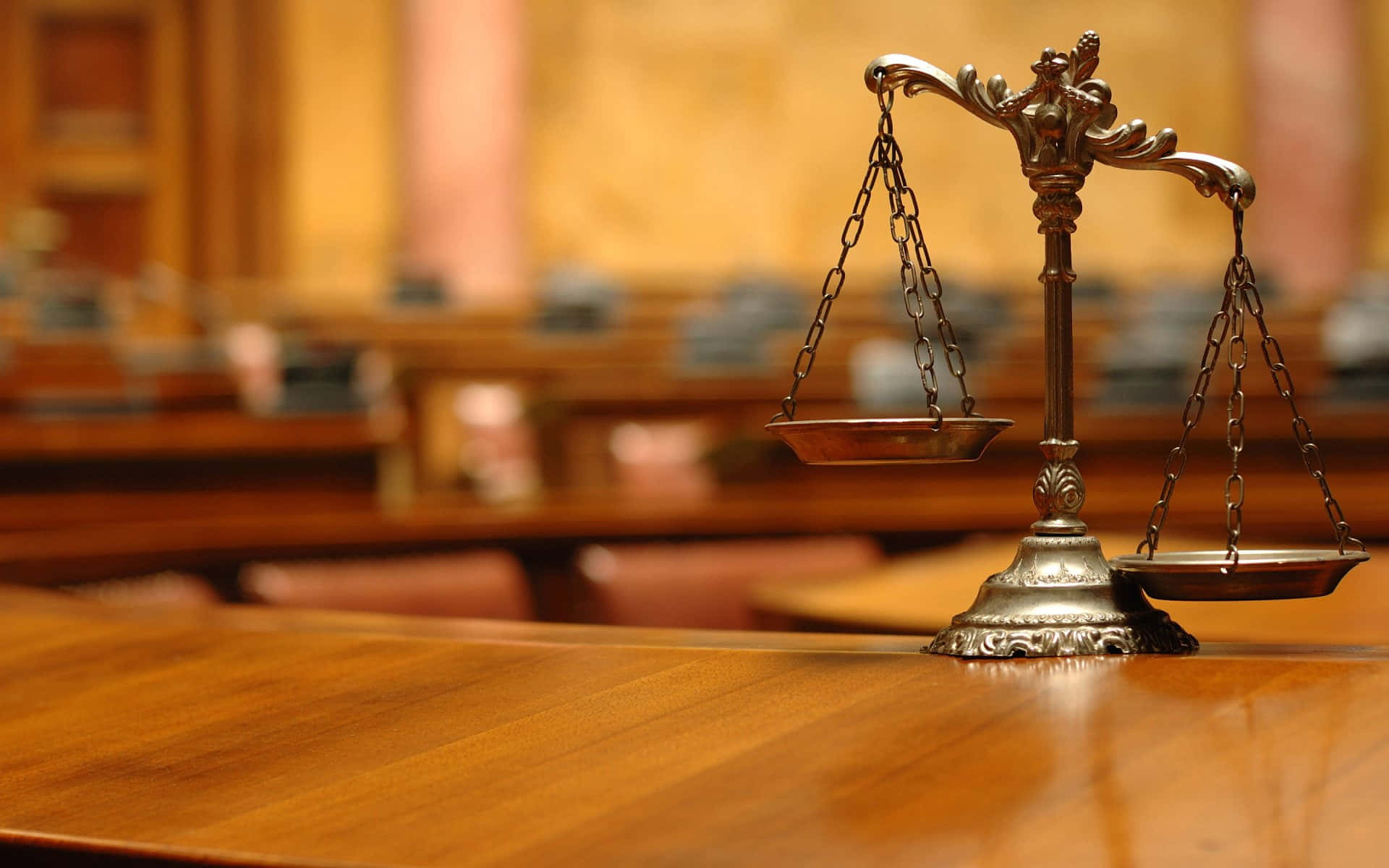 Una balanza de latón de la justicia sobre una mesa de madera en una sala de tribunal. — Igualitario Imagen Fondos de pantalla