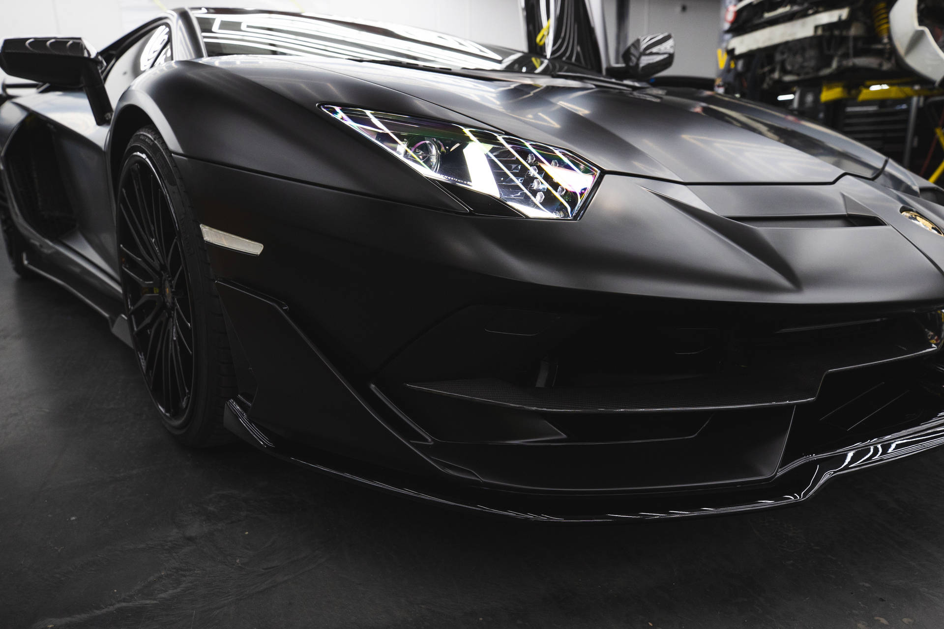 Mattschwarzer Lamborghini Aventador in einer Garage mit leuchtenden Scheinwerfern. — Schwarze Sportwagen Wallpaper