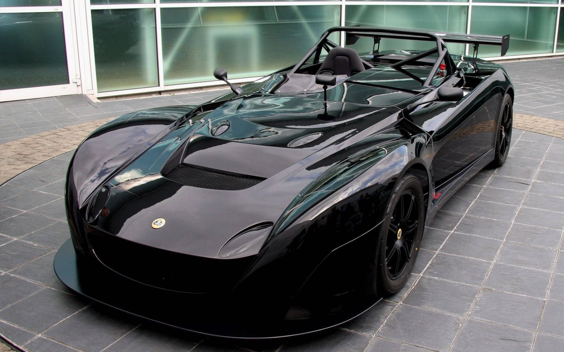 Schwarzer Lotus-Sportwagen mit Überrollkäfig auf gefliestem Patio geparkt. — Schwarze Sportwagen Wallpaper