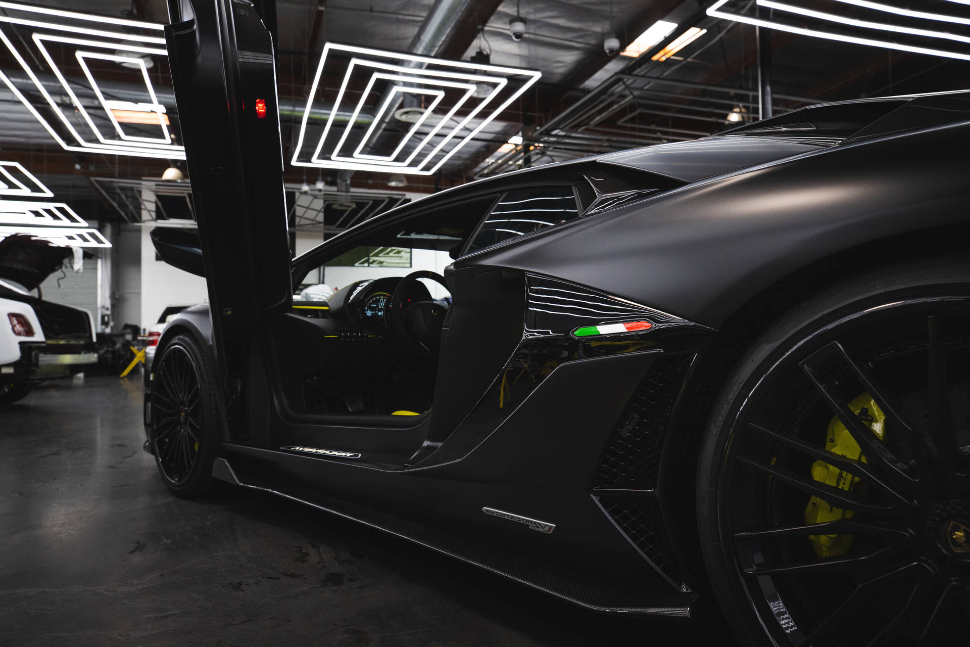Mattschwarzer Lamborghini mit geöffneten Flügeltüren in einer neonbeleuchteten Garage. — Schwarze Sportwagen Wallpaper