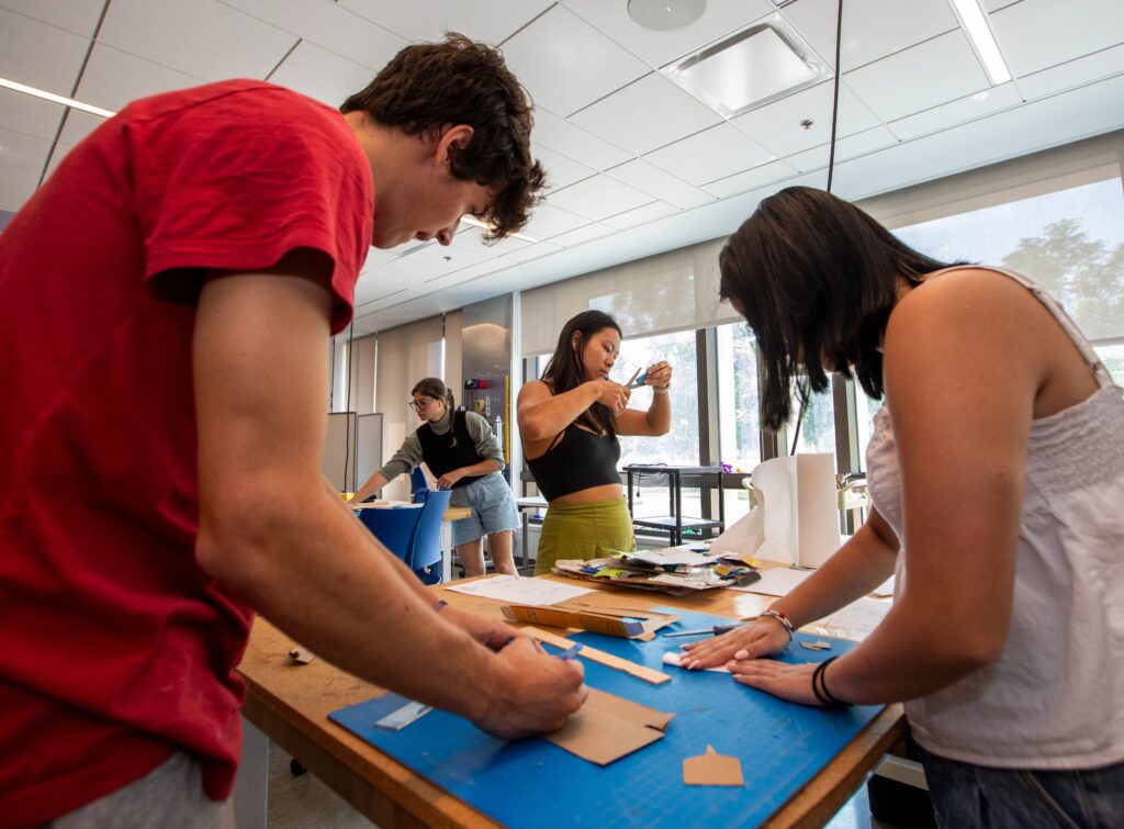 Four students work at tables in an engineering workshop