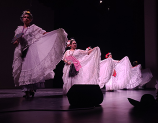 Students dancing on stage in white dresses