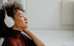 Adapting to the new normal: a young woman with headphones listening to a 5 minutes guided meditation