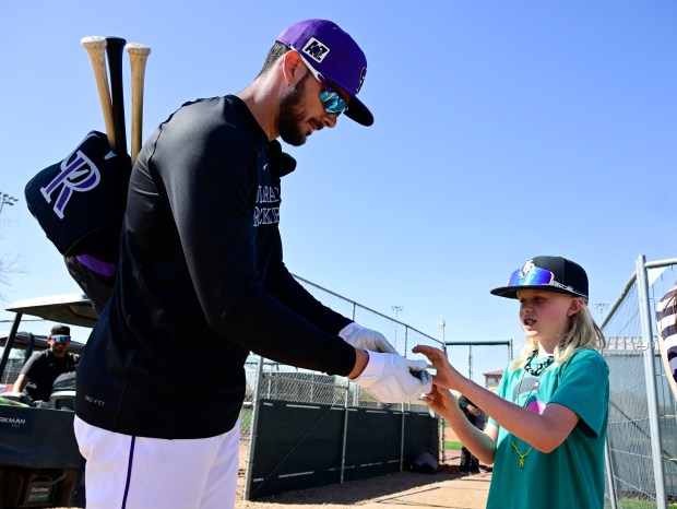 Rockies outfielder Kris Bryant hands over an autograph to Rory...