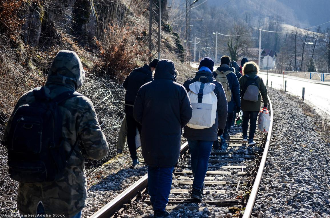 Skupina migrantov hodi po železniški progi.