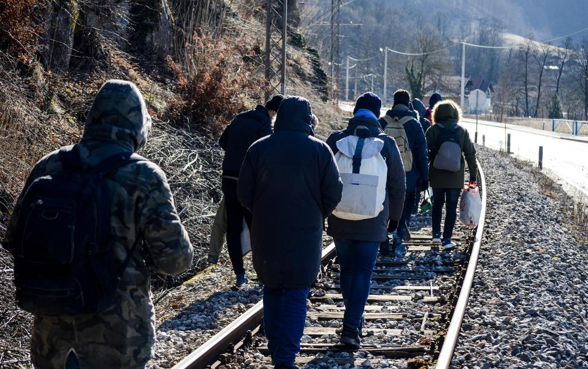 Un gruppo di migranti cammina lungo una linea ferroviaria. Tra le cause della migrazione ci sono guerra, conflitti e condizioni ambientali. ©Ajdin Kamber/AdobeStock