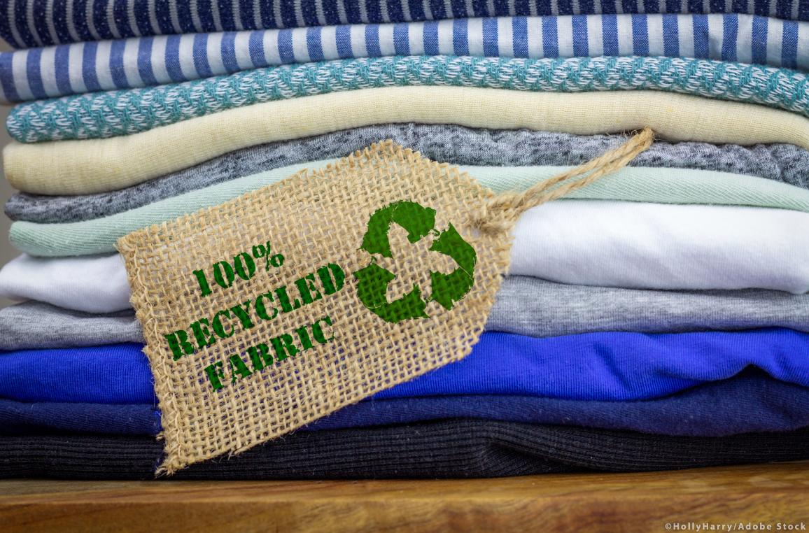 Recycle clothes icon on fabric label with 100% Recycled text. ©AdobeStock/HollyHarry