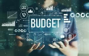 Photo describing a young man in the night with the two hands showing the word "budget" in a transparent screen