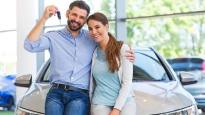 Photo of a happy couple with their new car and car keys.