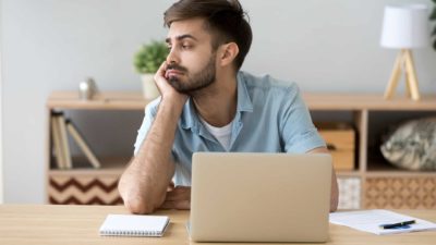 A bored man sits at his desk, flat after seeing the latest news on the share market.