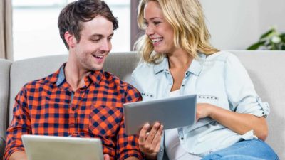 Happy man and woman looking at the share price on a tablet.