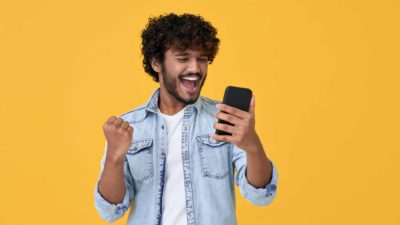 A man sees some good news on his phone and gives a little cheer.