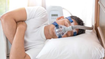 Man with a sleep apnoea mask on whilst sleeping.