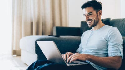 Man smiling at a laptop because of a rising share price.