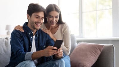 Smiling couple looking at a phone at a bargain opportunity.