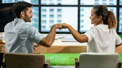 Happy work colleagues give each other a fist pump.