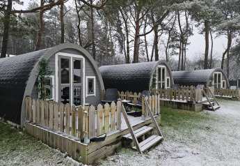 Kleine houten lodges met veranda’s met sneeuw in het bos bij Woodlodge, Wilsumer Berge, Duitsland.