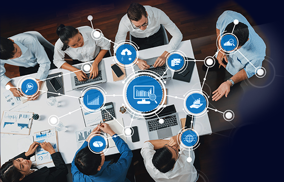 Overhead view of seven people at a table on laptops and in discussion