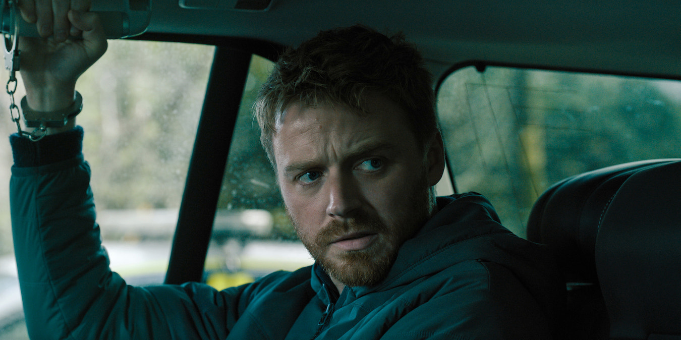 Jack Lowden as River Cartwright in 'Slow Horses' Season 4, shown here with his right wrist handcuffed to a car