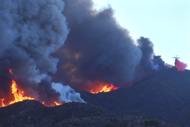 PACIFIC PALISADES, CALIFORNIA - JANUARY 07: A firefighting aircraft drops the fire retardant Phos-Chek as the Palisades Fire burns amid a powerful windstorm on January 7, 2025 in Pacific Palisades, California. The fast-moving wildfire is threatening homes in the coastal neighborhood amid intense Santa Ana Winds and dry conditions in Southern California.  (Photo by Mario Tama/Getty Images)