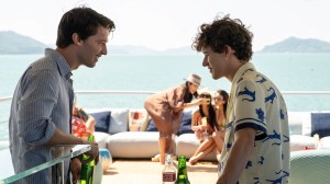 Two young men on a boat with young women and the horizon in the background; still from 'The White Lotus'