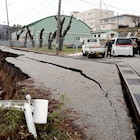 People stand next to large cracks in the pavement after evacuating into a street in the city of Wajima, Ishikawa prefecture on January 1, 2024, after a major 7.5 magnitude earthquake struck the Noto region in Ishikawa prefecture in the afternoon. Tsunami waves over a metre high hit central Japan on January 1 after a series of powerful earthquakes that damaged homes, closed highways and prompted authorities to urge people to run to higher ground. (Photo by Yusuke FUKUHARA / Yomiuri Shimbun / AFP) / Japan OUT / NO ARCHIVES - MANDATORY CREDIT: Yomiuri Shimbun