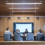 Looking into a conference room or board room meeting including people sitting around table in a room with international time clocks.