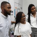 3 students in a lab looking at something outside of the picture.