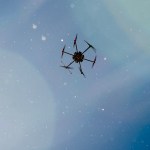 A drone in flight against blue skies.