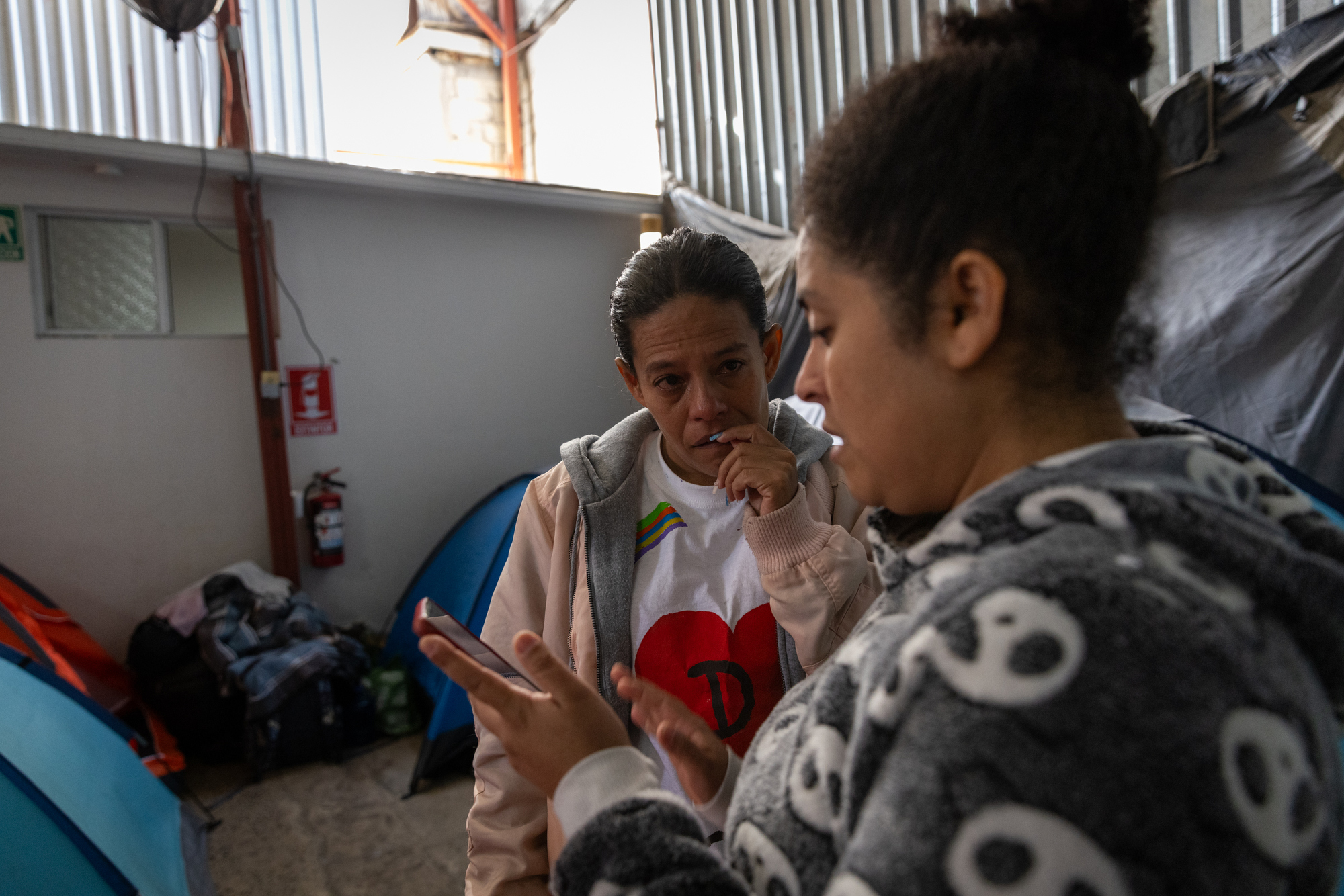 Milagro Gonzalez, of Venezuela, and Ivis Salgado, of Honduras, right, speak to friends in other cities who received the same news that their CBP One appointments were cancelled. on Monday, Jan. 20, 2025 in Tijuana, Mexico. (Ana Ramirez / The San Diego Union-Tribune)