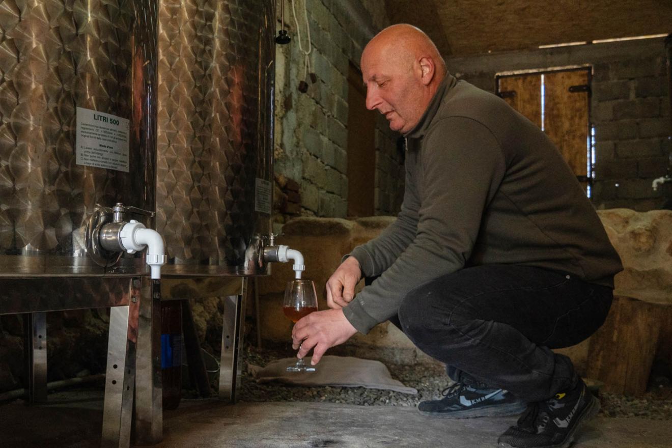 Un petit producteur de vin en Géorgie verse du vin dans un verre.