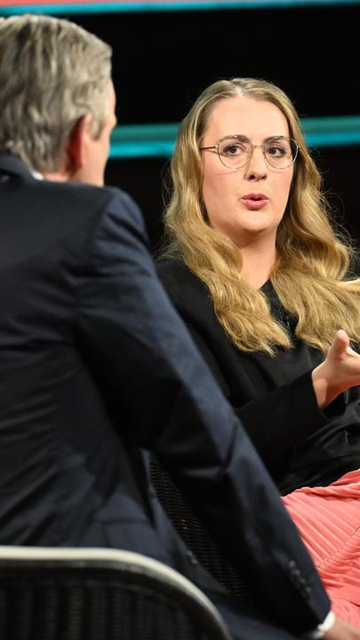 Grünen-Politikerin Katharina Dröge sitzt mit einem schwarzen Oberteil und einem korallfarbenden Rock im TV-Studio bei Markus Lanz.
